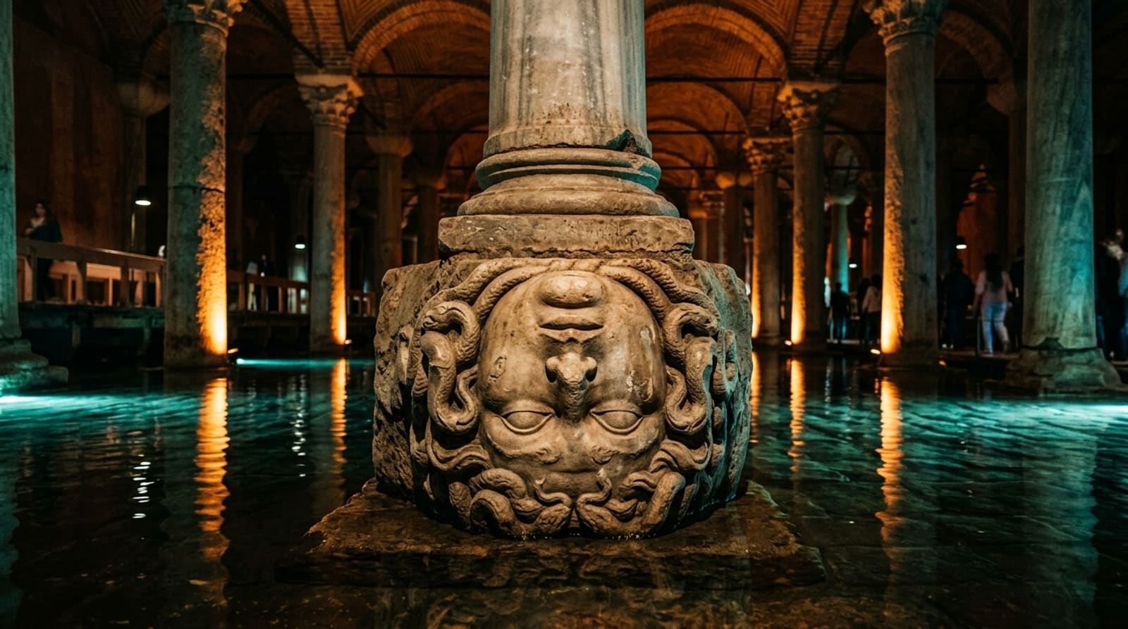 Upside-down Medusa head column base glowing in aquamarine light in a quiet corner of the Basilica Cistern